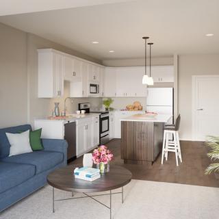 A modern open-concept living room and kitchen with neutral tones and contemporary furnishings.