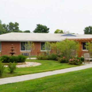A brick house with a well-maintained garden and a fountain in the front yard.