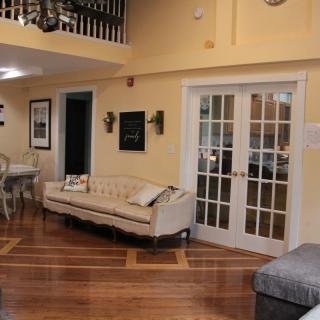 A cozy living room with elegant furniture, including a stylish sofa and a dining table, showcasing hardwood floors and French doors.