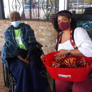 A caregiver and an elderly woman enjoying a moment outdoors, with the caregiver holding a basket filled with items.