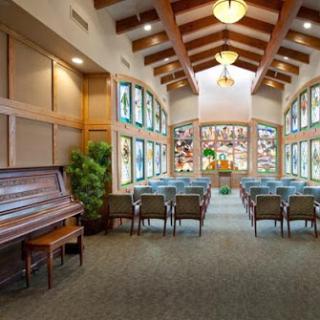 A cozy lounge area featuring wooden beams, a piano, and beautiful stained glass windows.