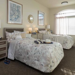 A cozy bedroom with two neatly made twin beds, complemented by floral bedding and stylish decor.