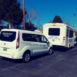 A van and a bus parked in a parking lot on a sunny day.