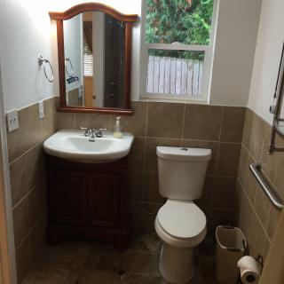 A clean and well-organized bathroom with a sink, mirror, toilet, and window.