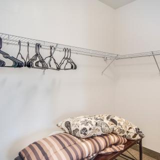 An organized closet with hangers and folded linens on shelves.