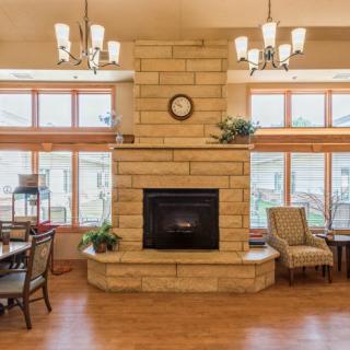 A cozy living room interior featuring a stone fireplace and large windows.