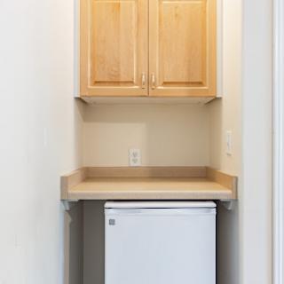 A clean and organized laundry nook featuring cabinets, a countertop, and a mini fridge.
