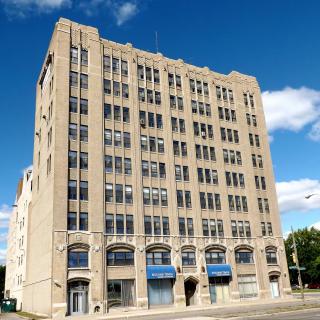 An urban office building with multiple floors and large windows against a clear blue sky.