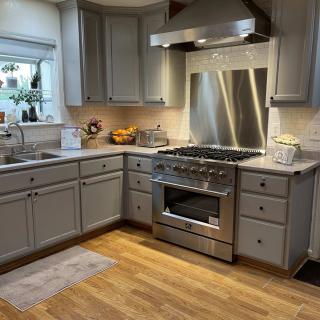 A modern kitchen with gray cabinets, a stainless steel stove, and hardwood floors.