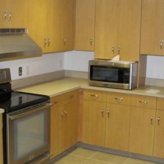 A modern kitchen with wooden cabinets, featuring a microwave and an oven.