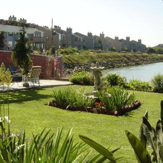 A beautifully landscaped garden by the riverside, featuring lush greenery and a serene water view.