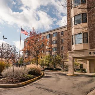 A multi-story building with an American flag flying outside, surrounded by trees under a partly cloudy sky.