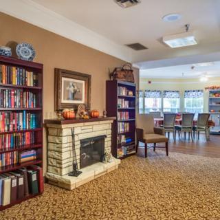 A cozy indoor library with bookshelves, a fireplace, and seating area.