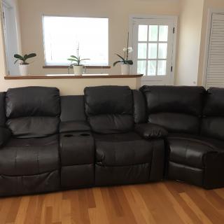 A black leather reclining sofa in a living room setting.