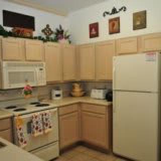 A cozy kitchen with light wood cabinets, featuring a refrigerator, microwave, and oven.