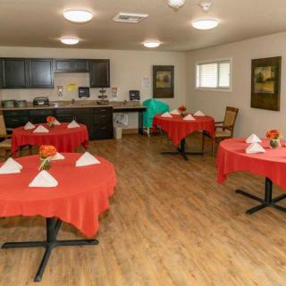 A neatly arranged dining room with red tablecloths and napkins, ready for guests.