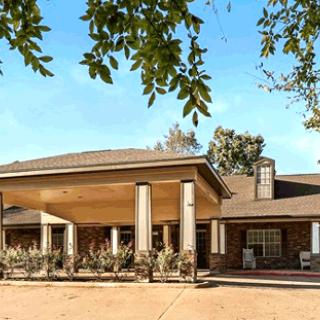A large house with a prominent porch and columns surrounded by trees.