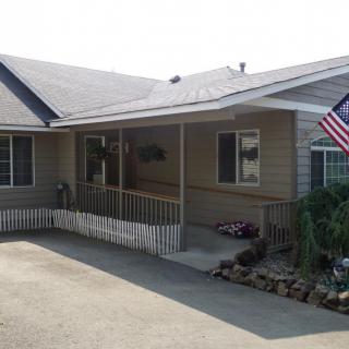 A single-story house with a porch, featuring an accessibility ramp and an American flag.