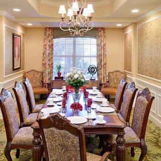 An elegant dining room set for a formal meal, featuring a long table with ornate chairs and a central chandelier.