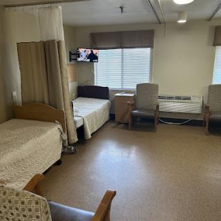 A view of a shared hospital room with two patient beds and a TV.