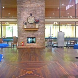 A spacious lobby featuring a central fireplace with a clock above it, complemented by modern seating and wooden floors.