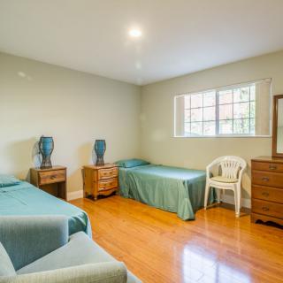 A simple bedroom with two beds and a wooden floor.