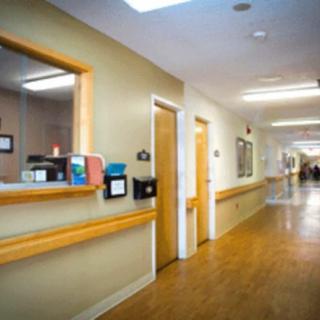 A hospital hallway with a reception area and wooden flooring.