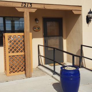 Entrance to a building with a blue pot and lattice structure beside the door.