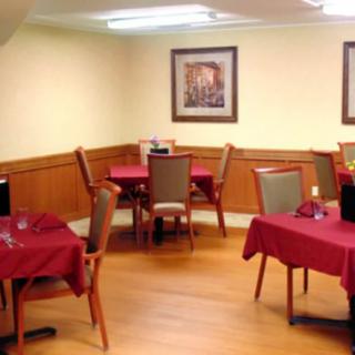 A cozy dining area with tables covered in red tablecloths, surrounded by wooden chairs.