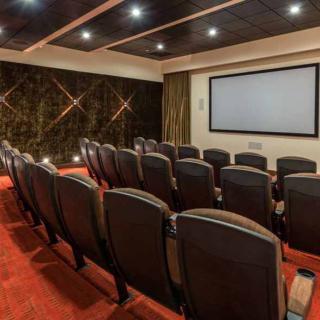 A cozy home theater with rows of comfortable seating facing a large screen.