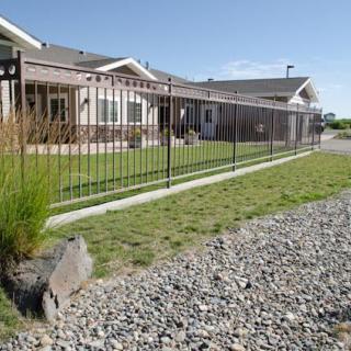 A suburban home with a fenced yard and gravel path.