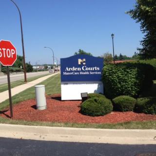 A healthcare facility sign near a stop sign, surrounded by well-maintained landscaping.