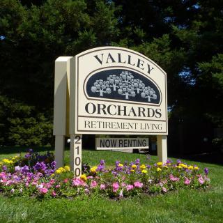 Sign for Valley Orchards Retirement Community surrounded by flowers.