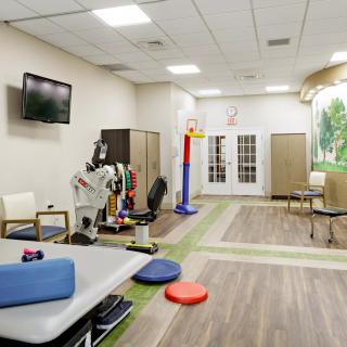 A bright rehabilitation room equipped with various physical therapy tools and exercise mats.