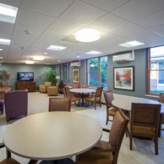 A cozy lounge area with tables, chairs, a television, and wall decor.
