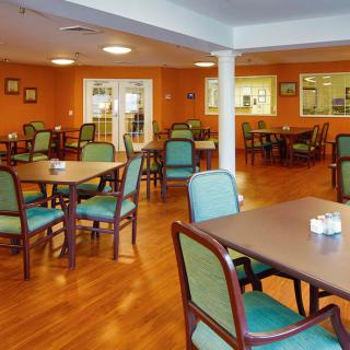 An empty dining area with orange walls and neatly arranged tables and chairs.