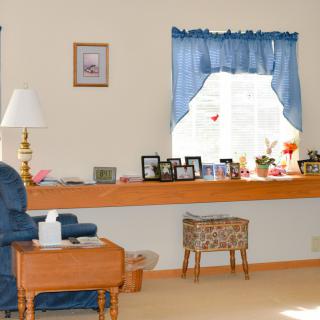 A cozy living room with a lamp, blue curtains, and various decorations on display.