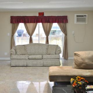 A cozy living room with a sofa, window curtains, and an air conditioner.