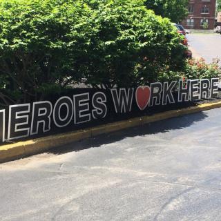 A sign reading 'Heroes Work Here' is displayed outdoors, expressing appreciation for workers.