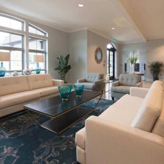 A modern living room with white sofas, a dark coffee table, and large windows providing ample natural light.