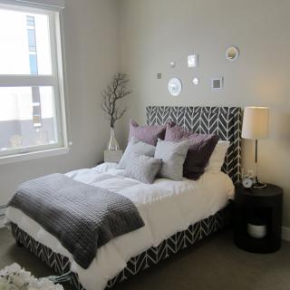 A cozy and stylish bedroom with a patterned headboard and soft, neutral decor.