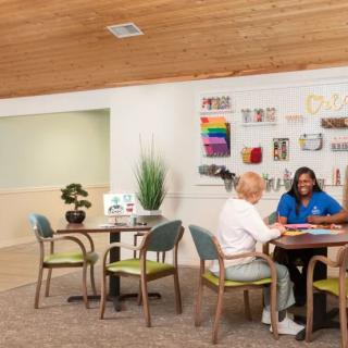 A caregiver interacting with elderly individuals in an assisted living activity room.