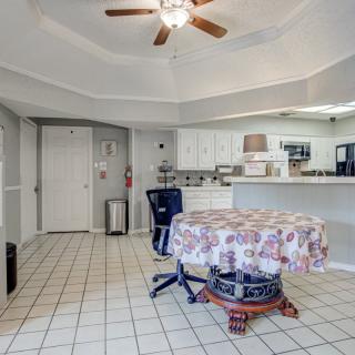 A spacious kitchen with a tiled floor, featuring a round table, chairs, and a ceiling fan overhead.