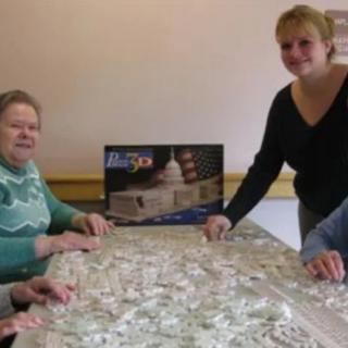 A group of people working on a puzzle together at a table indoors.