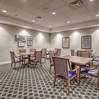 A conference room with tables and chairs set in a carpeted space, featuring artwork on the walls.