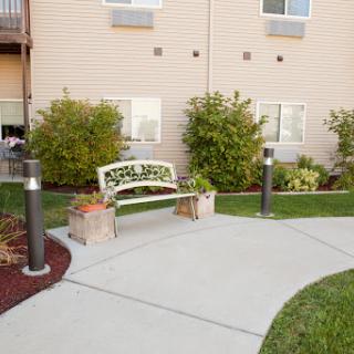 A serene outdoor area featuring a welcoming bench surrounded by lush greenery and a well-maintained pathway.