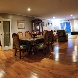A spacious dining room with hardwood flooring, featuring a long table and several chairs.