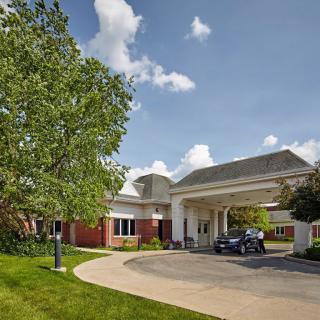 A healthcare facility with a welcoming entrance and driveway surrounded by greenery.