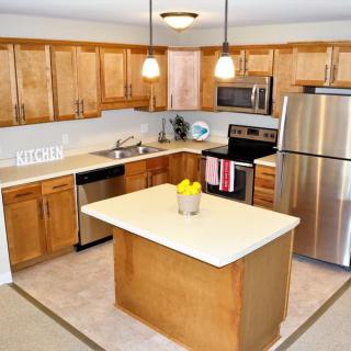 Modern kitchen with wooden cabinets, a central island, and stainless steel appliances.