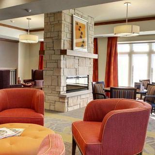 A cozy living room with modern decor featuring a central stone fireplace and comfortable seating.